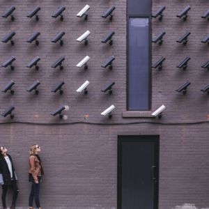 Two women facing security cameras mounted on wall above / CC0 Matthew Henry