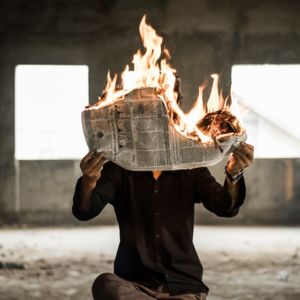 Person holding a burning newspaper Disinformation DSA Russia / CC0 nijwam-swargiary