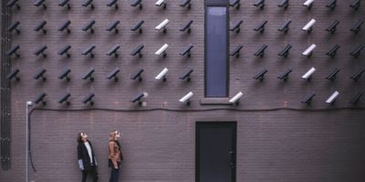 Two women facing security cameras mounted on wall above / CC0 Matthew Henry
