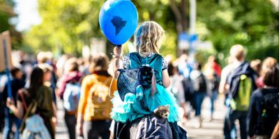 Child holding a balloon during a climate march/ CC0 Mika Baumeister