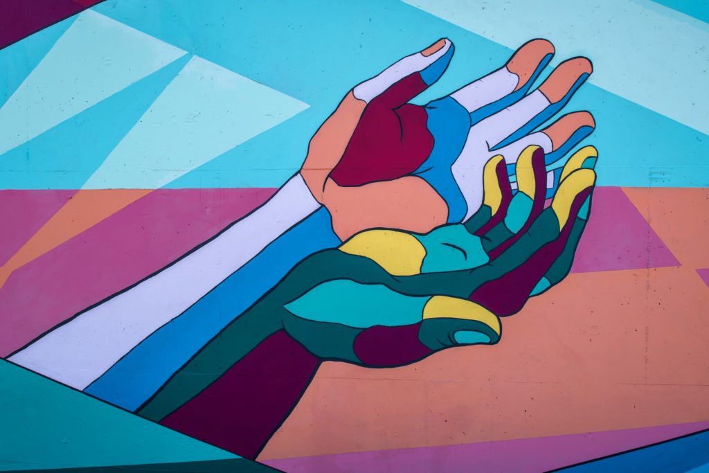 Artwork painting of colourful hands on a wall/ CC0 Tim Mossholder