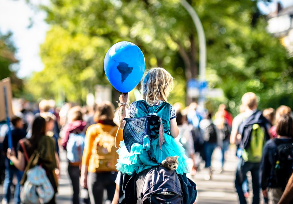 Child holding a balloon during a climate march/ CC0 Mika Baumeister