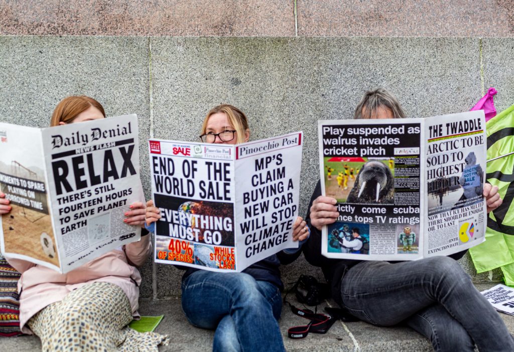 Activists sit in the central square of Glasgow reading today's climate newspaper