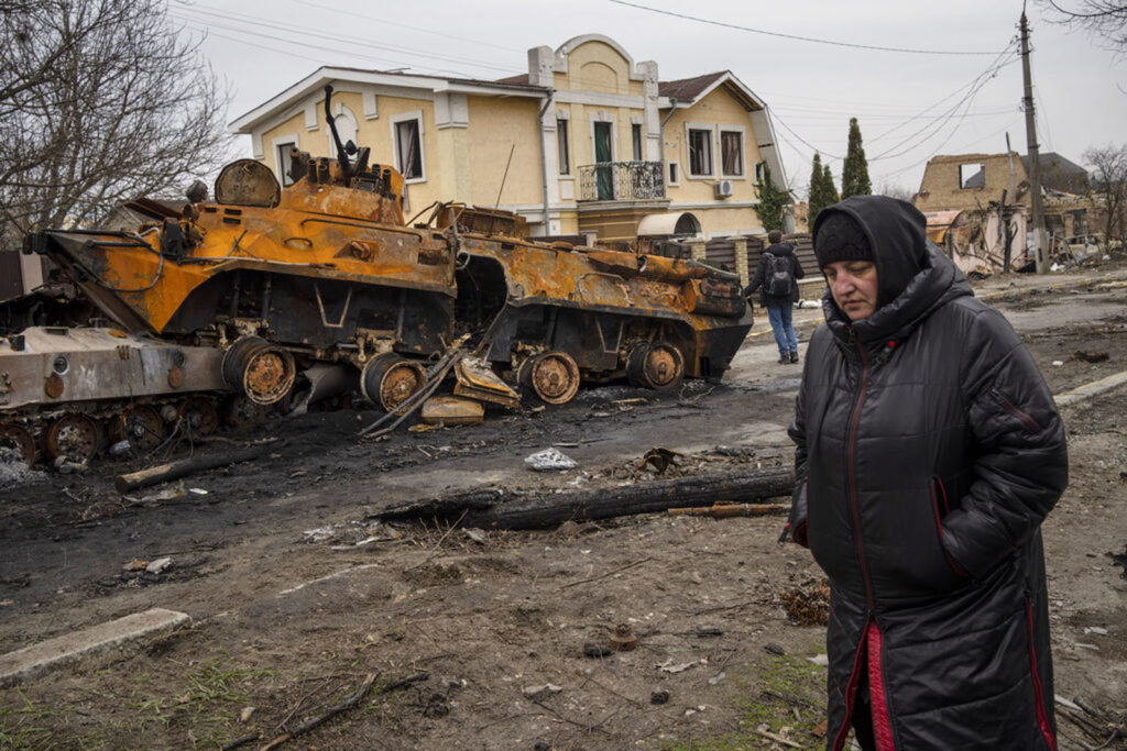 Woman walks by destroyed Russian armor vehicle in Bucha / manhhai/Flickr CC BY 2.0